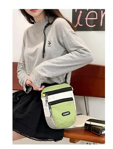 Detail der Crossbody-Tasche mit LUCKY-Schriftzug und Doppelreißverschluss am Modell