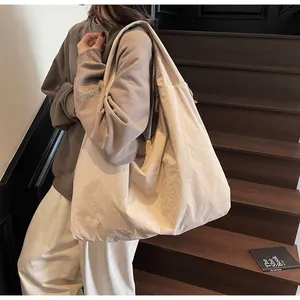 Detail of the oversized beige tote bag featuring wide shoulder straps and textured fabric