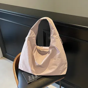 Light pink oversized casual tote bag in crinkled nylon fabric on a black chair
