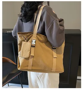 Detail of khaki large tote bag with buckle and detachable mini pouch shown on model