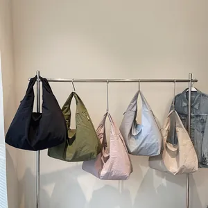 Minimalist crescent tote bag in five colors shown hanging on a modern display rack