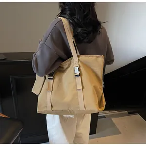 Detail view of khaki large capacity canvas tote bag worn by a model in casual style
