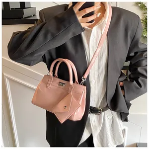 Détail du sac à main en cuir verni rose avec serrure argentée et mini pochette triangle