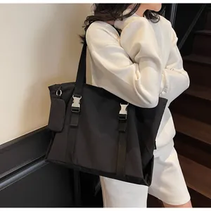 Detail view of large black nylon tote bag with metal buckles and mini side pouch