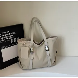 Close-up of beige tote bag featuring silver buckle straps and a matching mini pouch