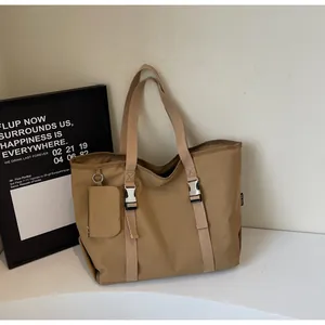 Detail of khaki nylon tote bag with silver buckles and a round coin purse attachment
