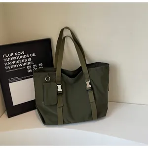 Macro view of olive green tote bag showing metallic buckle and detachable mini pouch