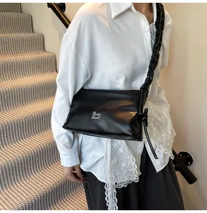 Dettaglio borsa in pelle nera con logo argento e tracolla arricciata di tendenza