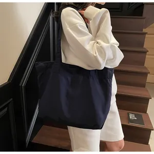 Detailansicht der tiefblauen Canvas-Einkaufstasche mit breitem Schultergurt am Model