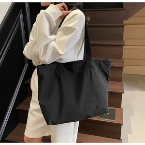 Detail einer großen schwarzen Canvas-Tragetasche getragen von einem Model auf der Treppe