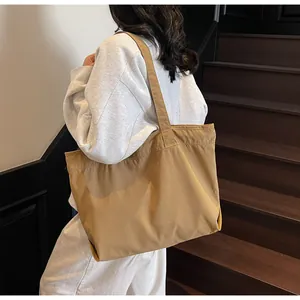 Seitenansicht eines großen khakifarbenen Canvas-Shoppers, getragen von einem Modell
