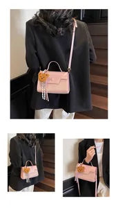 Detail of pink leather handbag showing textured pattern, teddy charm and striped ribbon
