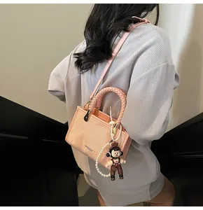 Dettaglio borsa quadrata rosa con manico intrecciato e tracolla di perle elegante