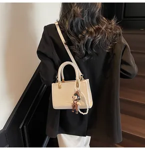 Borsa a tracolla crema con manico intrecciato e ciondoli su scale di legno