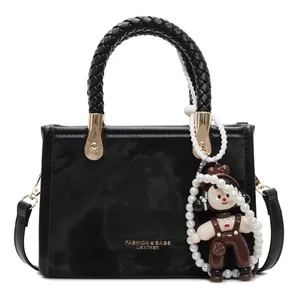 Elegante borsa nera con manico intrecciato, catena di perle e ciondolo bambola bimbo