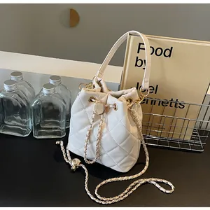 Detailed view of beige quilted bucket bag with gold chain drawstring and smooth texture