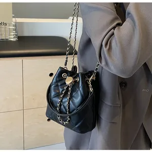 Detail of black quilted leather bucket bag with gold chain strap and drawstring closure
