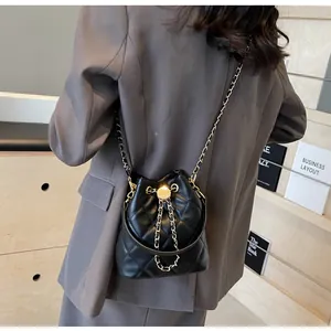 Detail of black quilted bucket bag with gold chain strap and drawstring closure