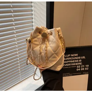 Close-up of cream quilted bucket bag with gold chain and metal drawstring ball detail