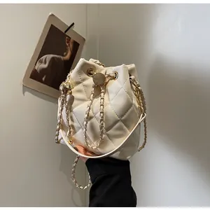Detail of cream quilted bucket bag with gold chain drawstring and metal ball charm