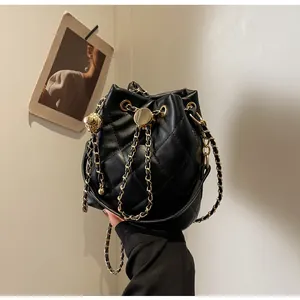 Detail of black quilted bucket bag featuring gold lion head clasp and chain drawstring
