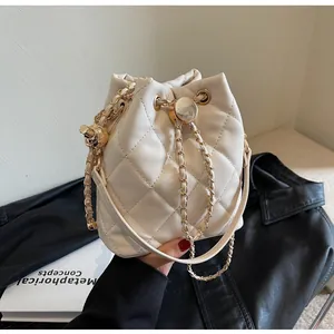 Detail of off-white quilted bucket bag with gold chain and sphere pendant charm