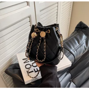 Detail of black quilted leather bucket bag featuring gold chain strap with adjustment ball