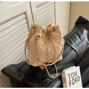 Detail of beige quilted bucket bag with golden chain strap and drawstring closure
