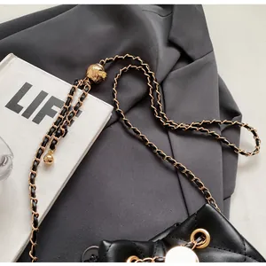 Detail of black quilted leather bag featuring gold chain and adjustable metal ball buckle