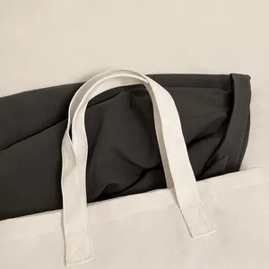 Detalle de bolso de lona blanca con costuras cruzadas reforzadas en las asas fuertes