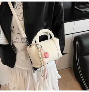Detail of lychee textured bucket bag featuring decorative ribbon and heart charm
