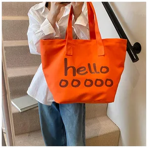 Detailweergave van grote oranje canvas shopper met bruine tekst hello ooooo print
