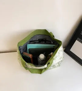 Spacious interior of a green canvas tote bag showing storage for a tablet and umbrella