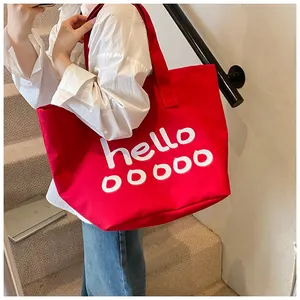 Gedetailleerd zicht van de rode canvas shopper met witte tekst op de schouder