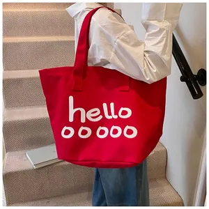 Detail van rode canvas draagtas met witte hello-tekstprint op een trap binnenshuis