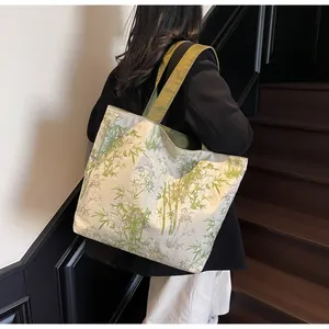 Detail of canvas tote bag featuring green bamboo ink print and wide shoulder straps