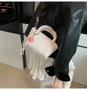 Detail view of lychee pattern leather handbag with heart charm and decorative scarf