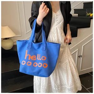 Blauwe canvas draagtas met oranje hello-print opzij getoond op een model