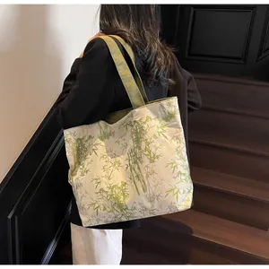 Detail shot of canvas tote bag with green bamboo prints and dark green straps