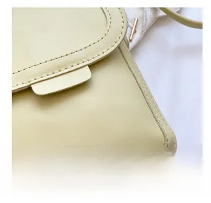 Detail shot of precise stitching and leather texture on a cream crossbody phone bag