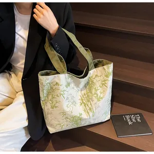 Close-up of canvas tote bag with bamboo leaf print on a dark wooden staircase