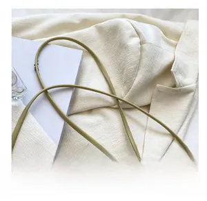 Detail of light green leather mini bag with thin knotted shoulder strap and gold hardware