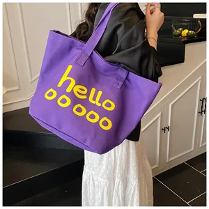 Detail van de paarse canvas shopper met gele tekst gedragen door een model op de trap
