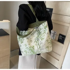 Detail of bamboo print tote bag on a model featuring green straps and spacious design