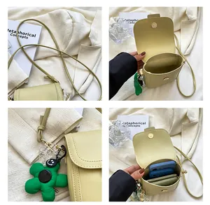 Detail of light green crossbody phone bag showing interior capacity and flower charm