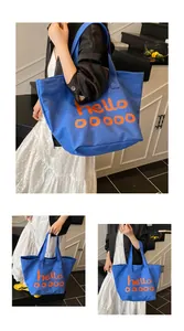 Detailoverzicht van de blauwe canvas tote bag met oranje letters en dubbele handvatten