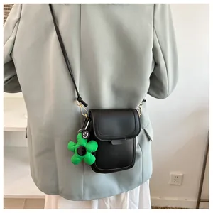Detailed back view of a minimalist black crossbody phone bag with green plush flower charm