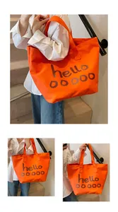 Gedetailleerde weergave van een oranje canvas draagtas met artistieke letters en stevige hengsels