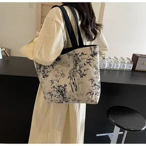Detailed view of canvas tote bag with ink bamboo print worn on shoulder