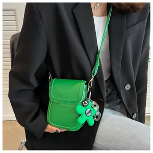Chic green mini crossbody bag with floral smiley charm worn on black blazer outfit
